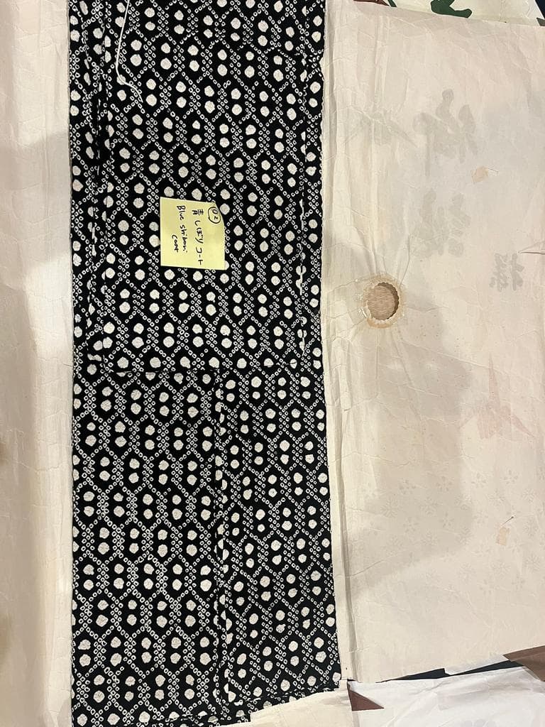 Folded black and white coat with kikkō pattern.