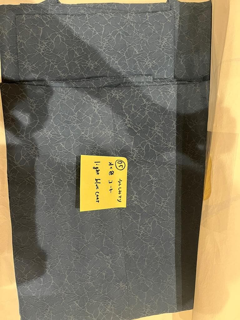 Folded light blue coat with subtle pattern.