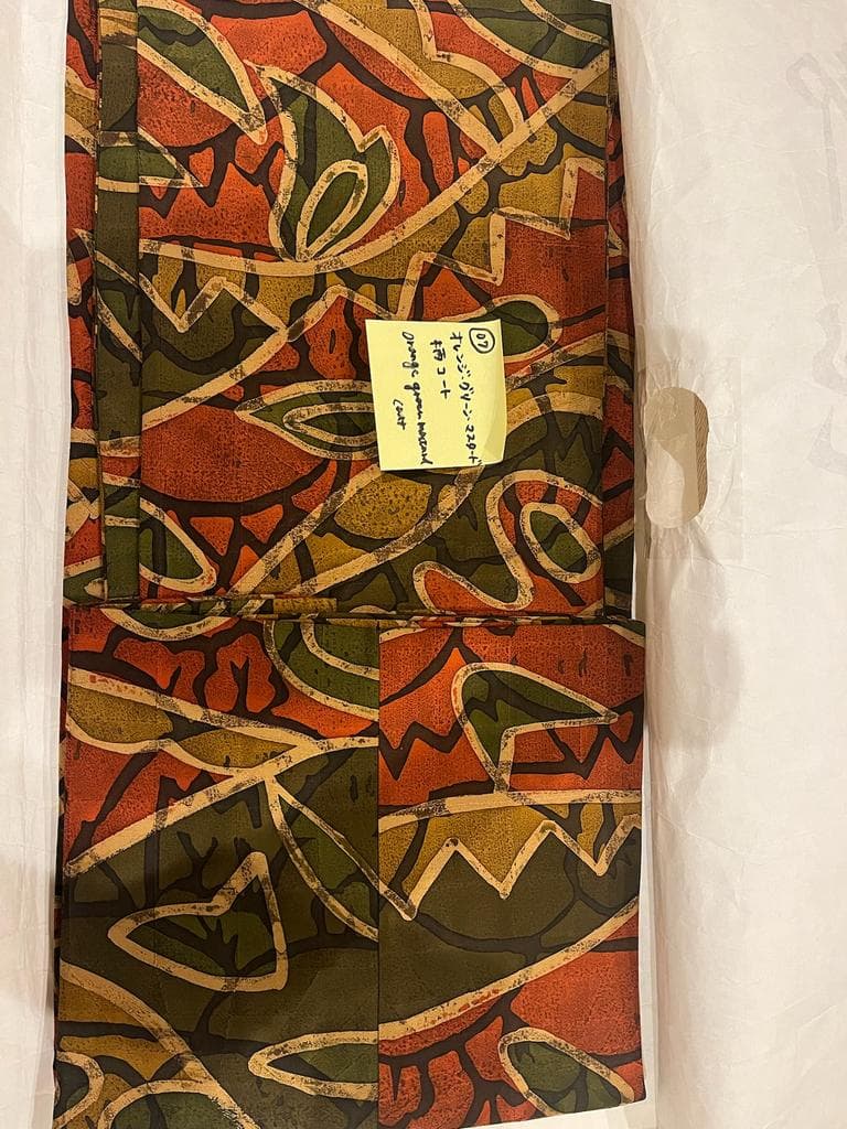 Folded coat with orange and green abstract pattern.