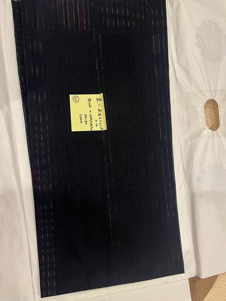 Close-up of black coat with red stripes.