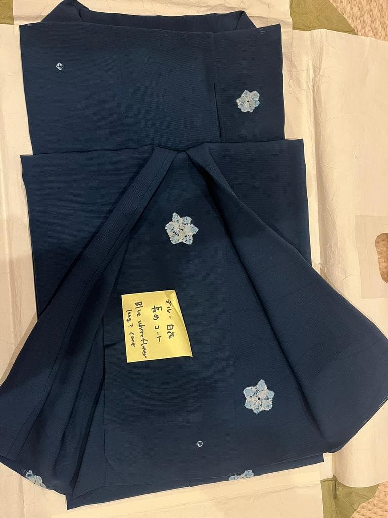Folded blue coat with floral motifs and crest.