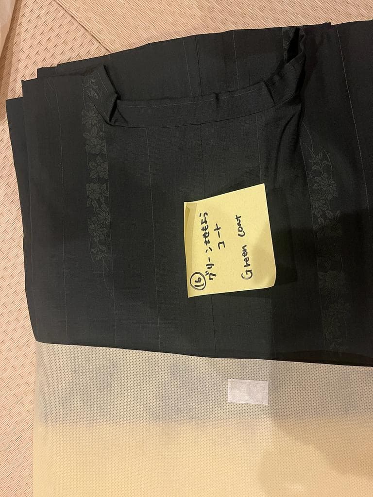 Folded green coat with floral pattern and handwritten note.